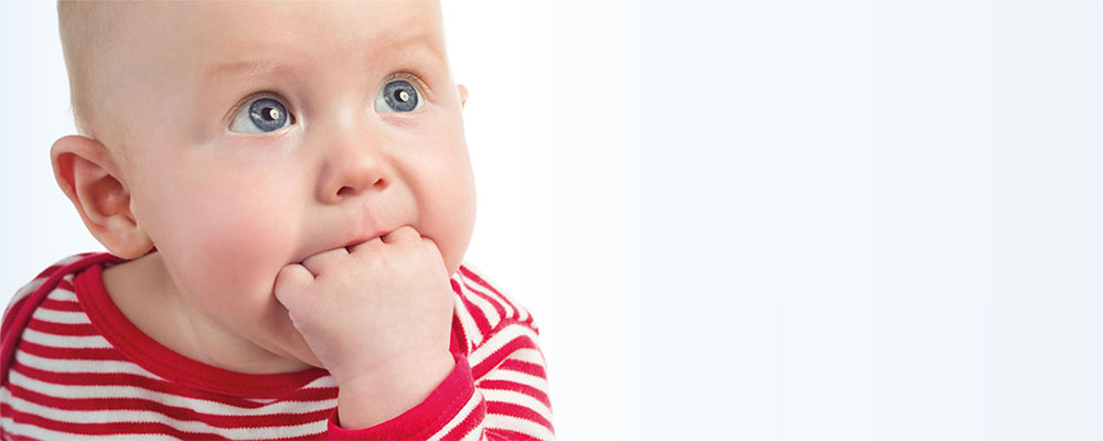 Babys machen intuitiv das Richtige: Sie schieben das Händchen oder die Faust in den Mund und kauen darauf herum. Ein Kleinkind schiebt sich die Faust in den Mund.
